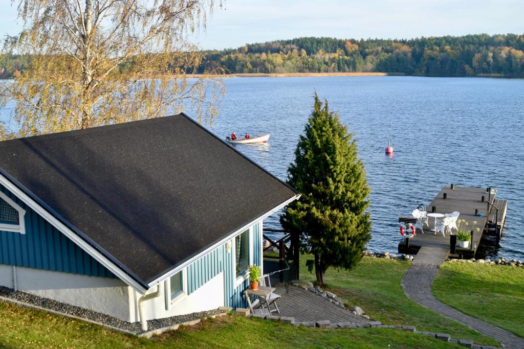 奥克什贝里亚Sjöstuga/gästhus i skärgården.的湖畔的房屋,有船