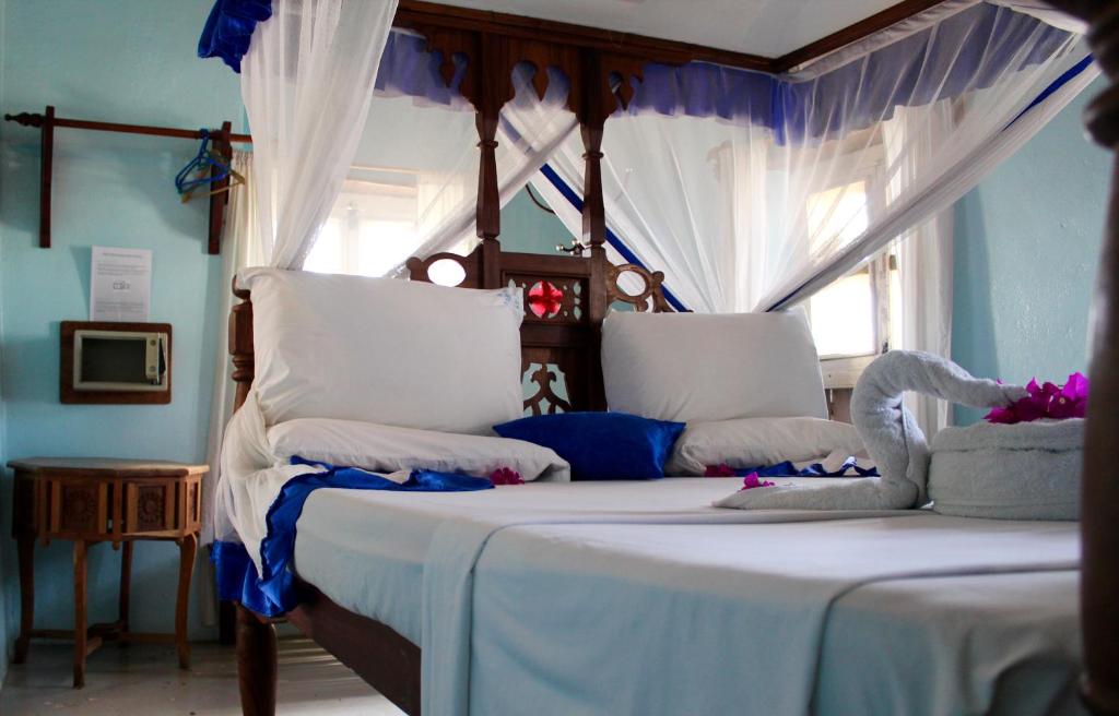 桑给巴尔萨尔姆公主宾馆的一间卧室配有两张白色和蓝色的床