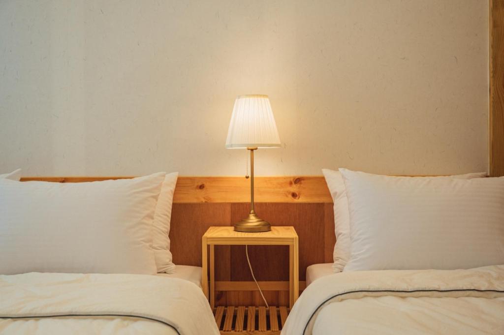 庆州Hanok Stay Seowa的一张桌子上的灯,旁边是两张床