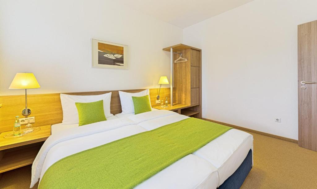 巴特塞京根Sapia Hotel St. Fridolin的卧室配有带绿色枕头的大型白色床