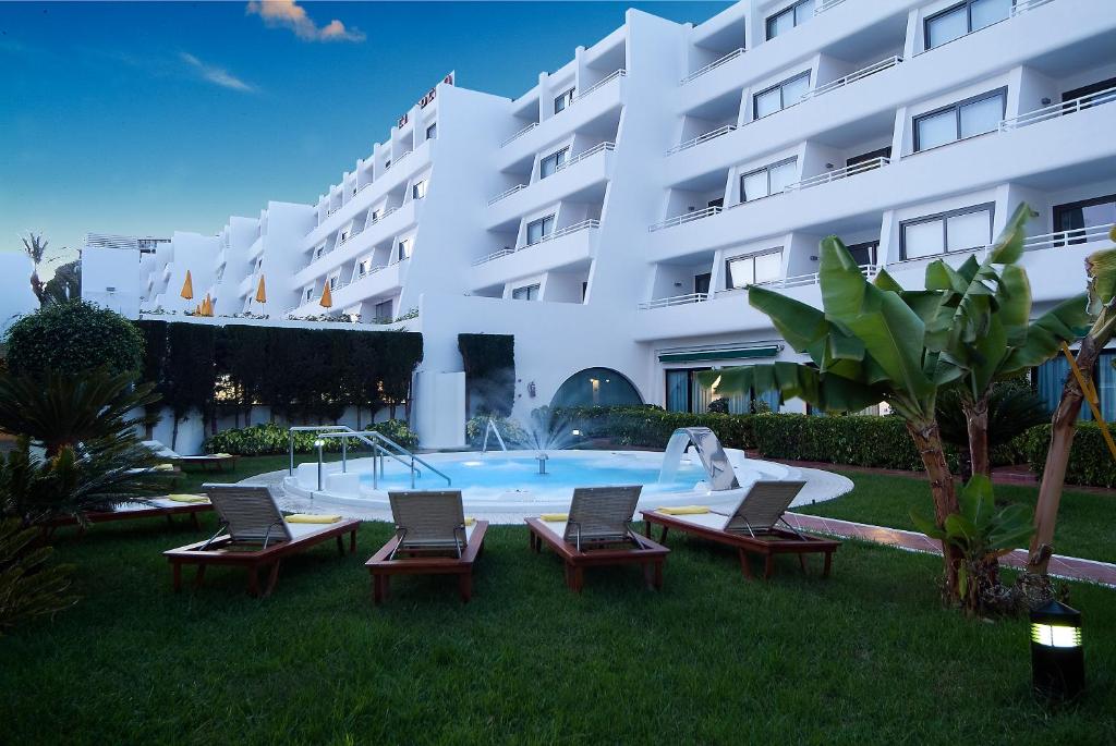 波多黎各埃尔格列柯酒店的一座带椅子和游泳池的大型白色建筑