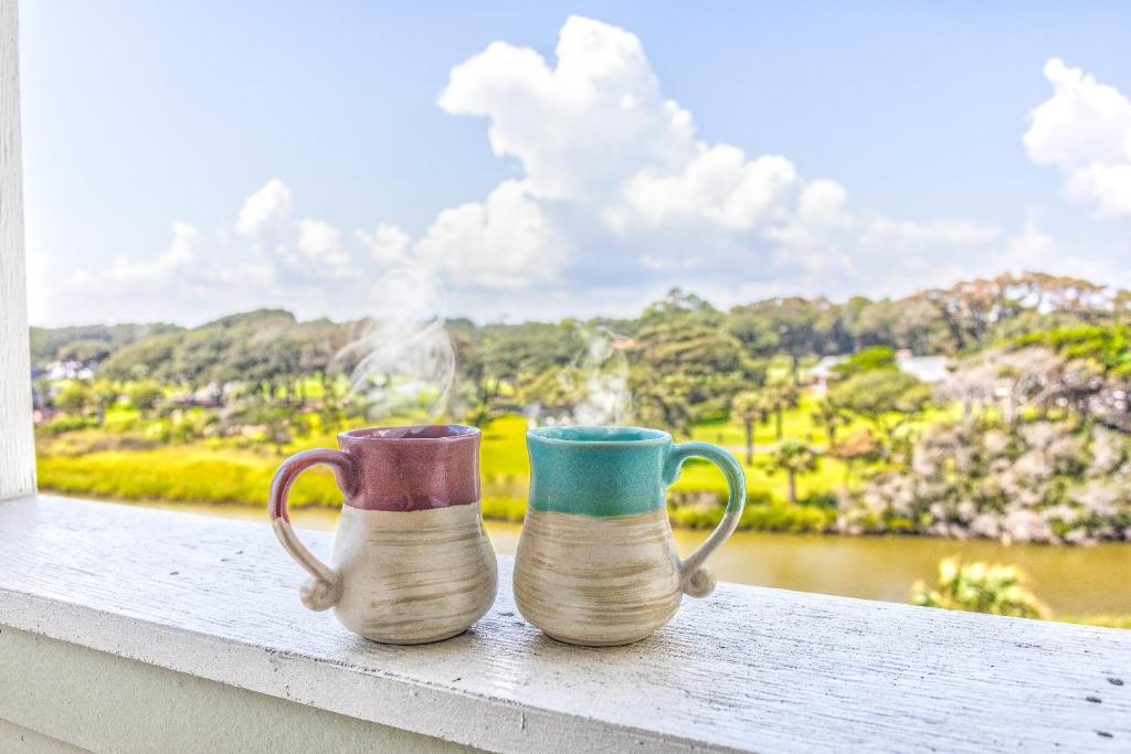 默特尔比奇ONE More Sandy Day - 2BR 2BA Beach Condo, Sleeps 6的两个咖啡杯坐在窗台上,享有美景