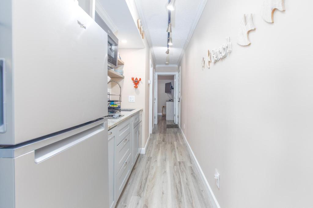 默特尔比奇ONE More Sandy Day - 2BR 2BA Beach Condo, Sleeps 6的厨房配有白色橱柜和硬木地板。