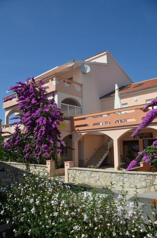诺瓦利娅Apartments Jadranka的一座在前面布满紫色花的建筑