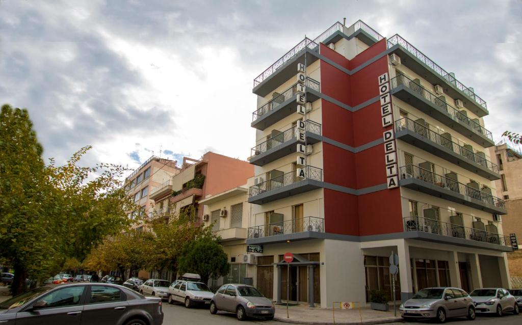 雅典雅典三角洲酒店 的一座红色的建筑,前面有汽车停放