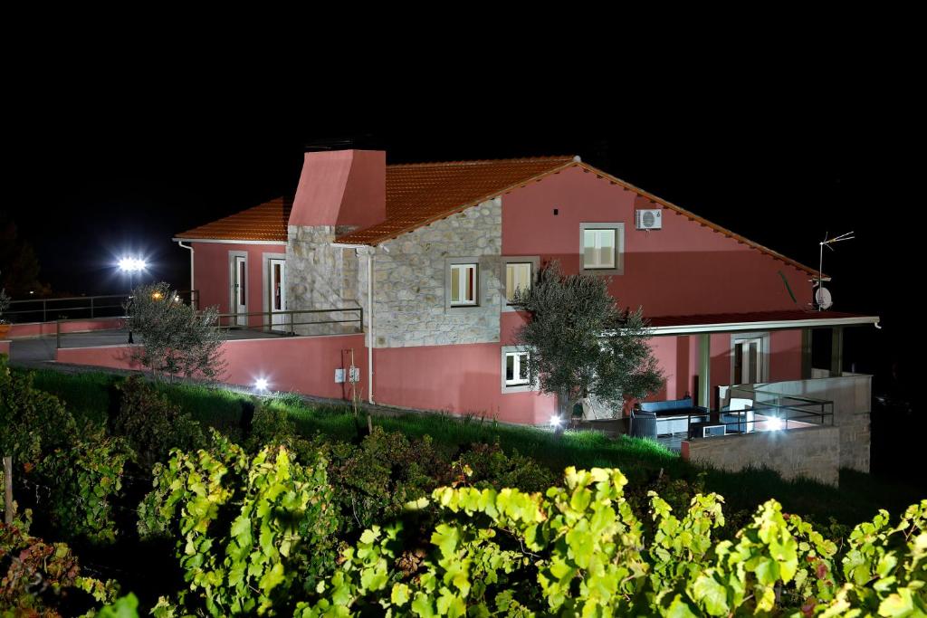 Foz do Sabor奥拉赖斯杜罗乡村民宿的一座大型的红色房子,晚上有葡萄园