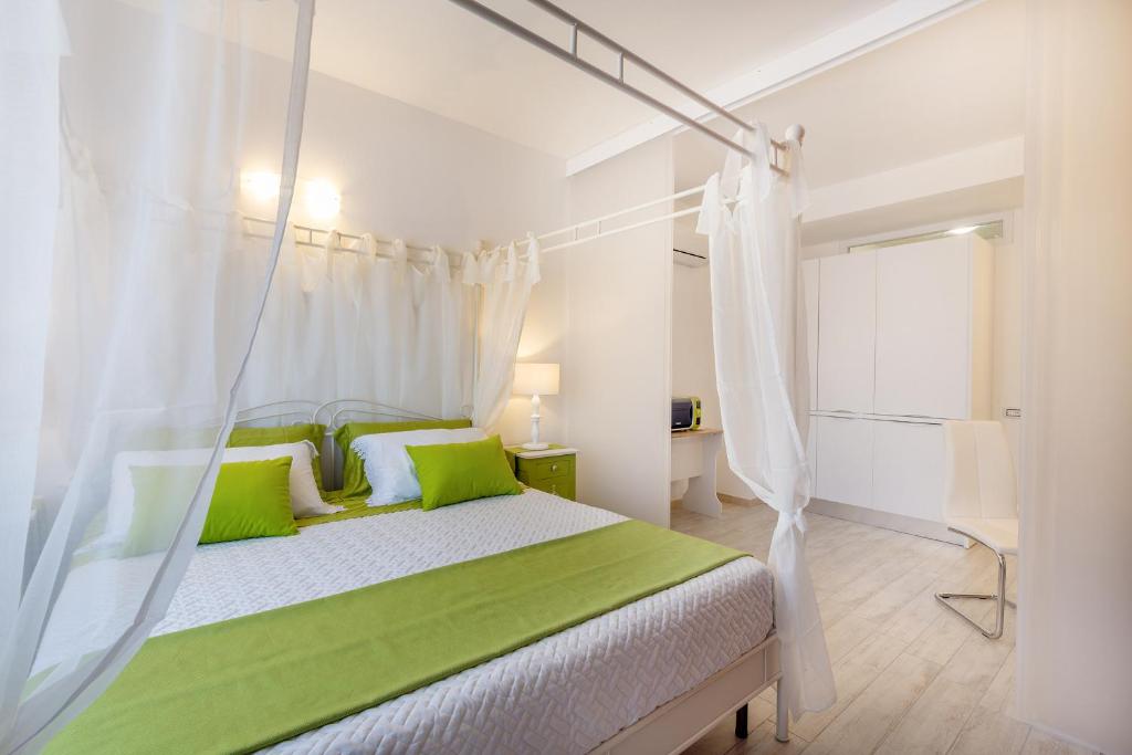 卡利亚里赛特科利宾馆的一间卧室配有一张带绿色枕头的天蓬床