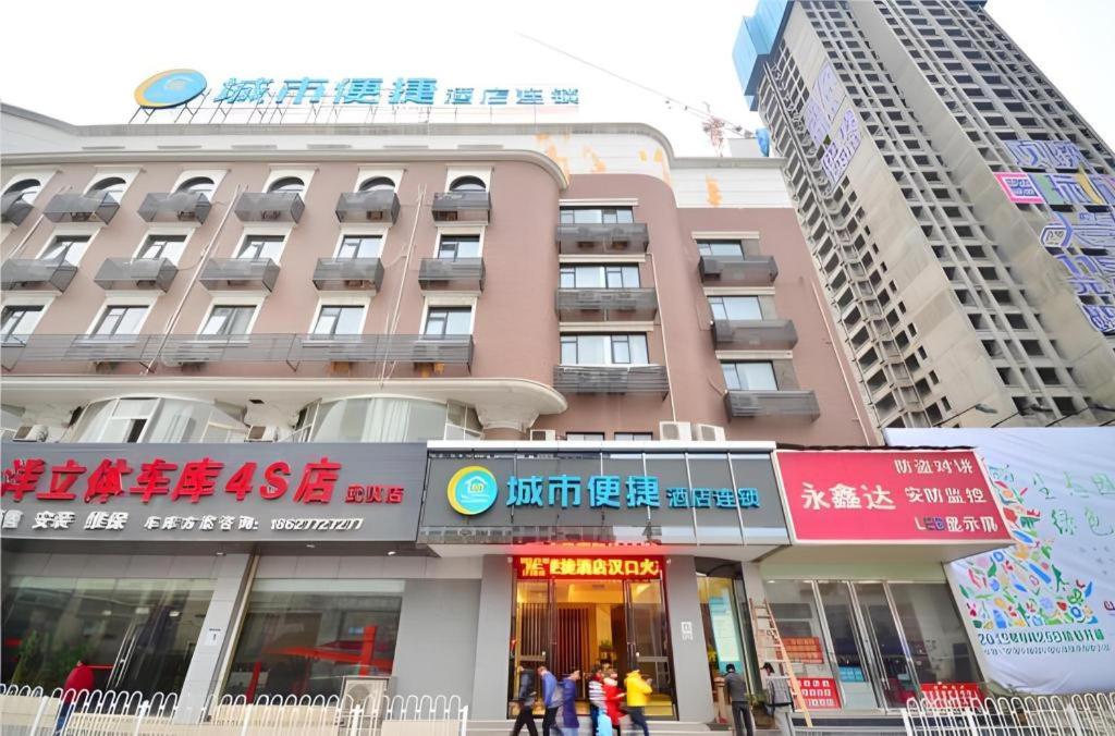 武汉City Comfort Inn Hankou Railway Station Tangjiadun Wanda Plaza的一座大型建筑,前面的人在步行