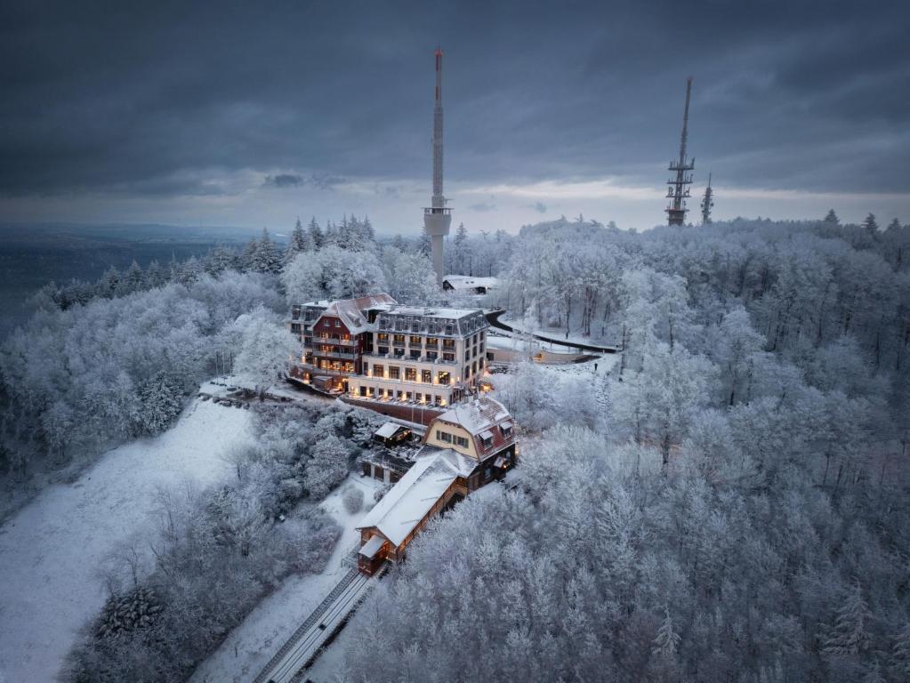 海德堡Berggasthof Königstuhl的雪地里建筑物旁的两列火车