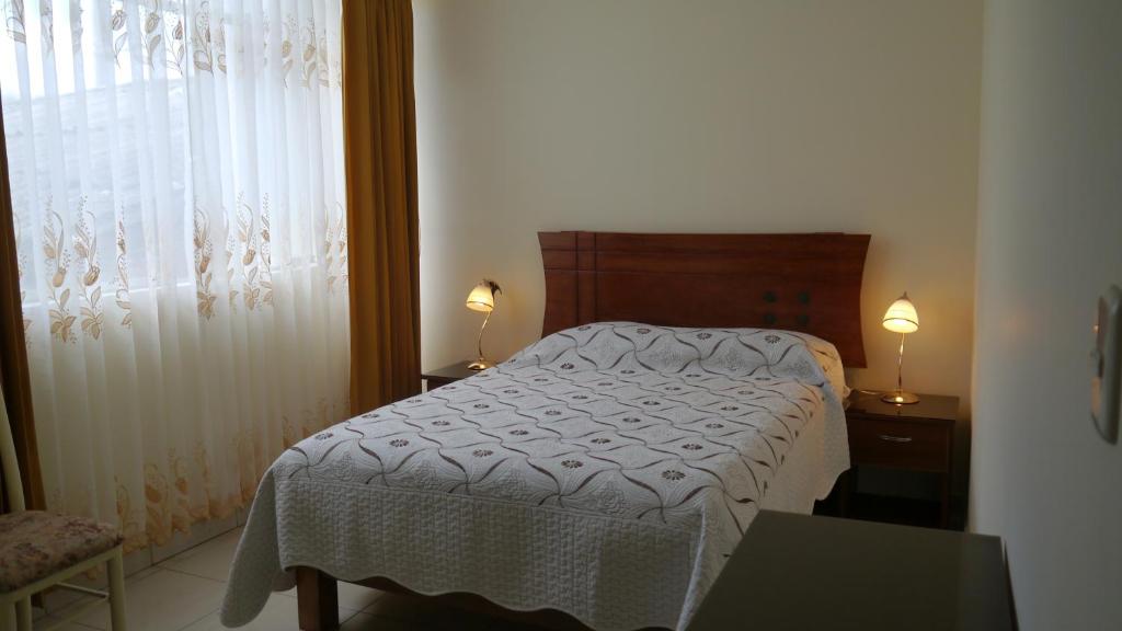 安达韦拉斯El Parque Hotel的卧室配有一张带白色棉被的床和窗户。
