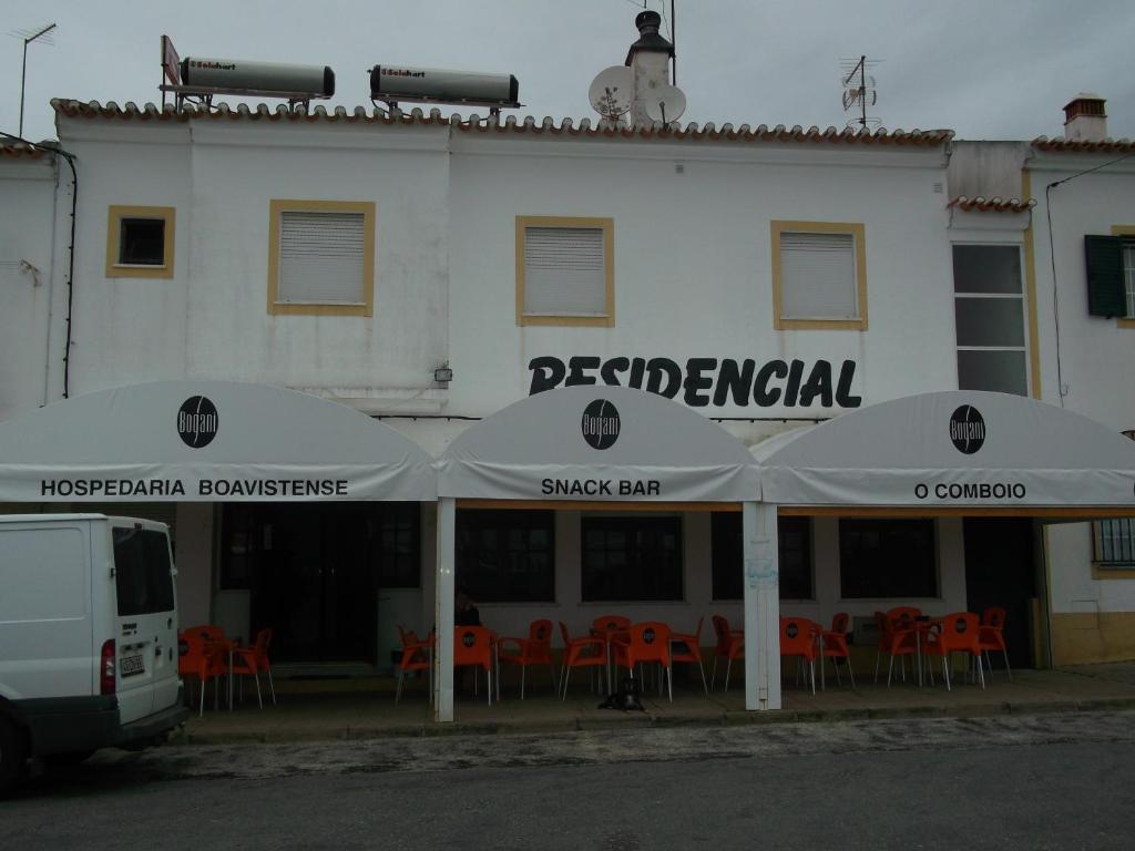 奥德米拉Alojamento local Boavistense的前面有桌子和遮阳伞的白色建筑