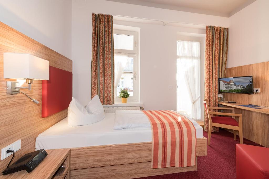 宾茨Strandhotel zur Promenade的配有一张床和一张书桌的酒店客房
