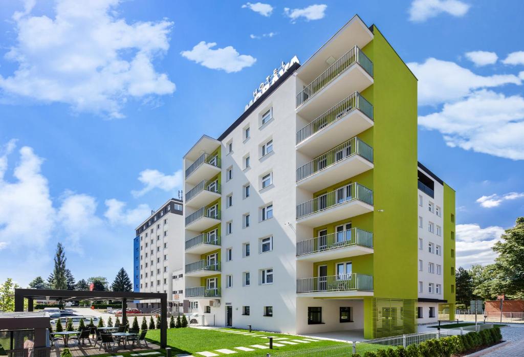 奥特罗科维采摩拉瓦酒店的公寓大楼拥有绿色和白色的外观