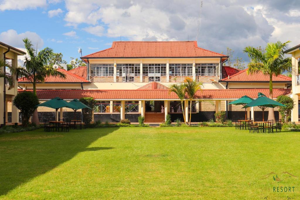 纳库鲁Lake Bogoria Spa Kabarak的院子内带桌子和遮阳伞的建筑