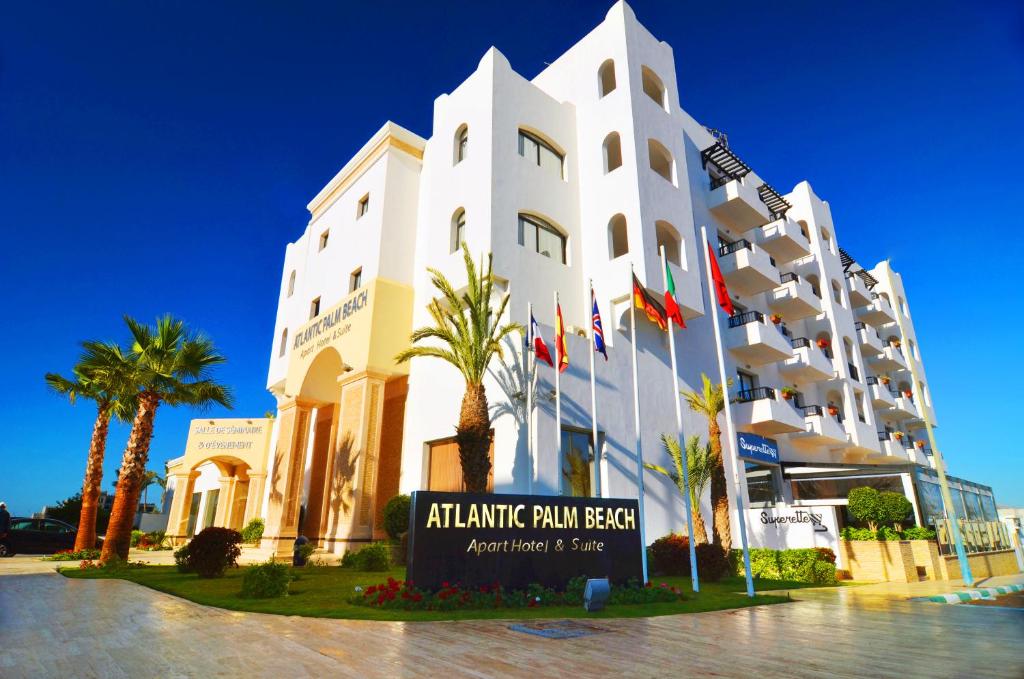 阿加迪尔大西洋棕榈滩公寓式酒店的一座白色的大建筑,前面有棕榈树