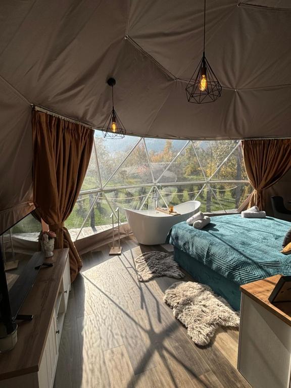 BălanGreen Garden Glamping Retezat的一间带浴缸和大窗户的卧室