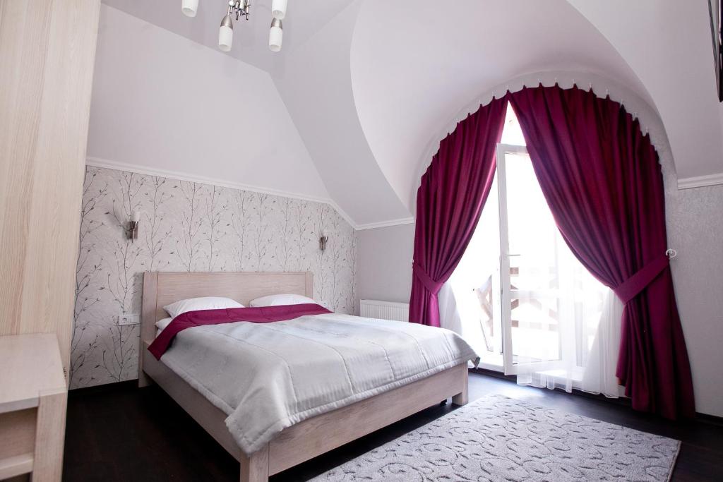 文尼察马尔森酒店的一间卧室配有一张带紫色窗帘的床和窗户。