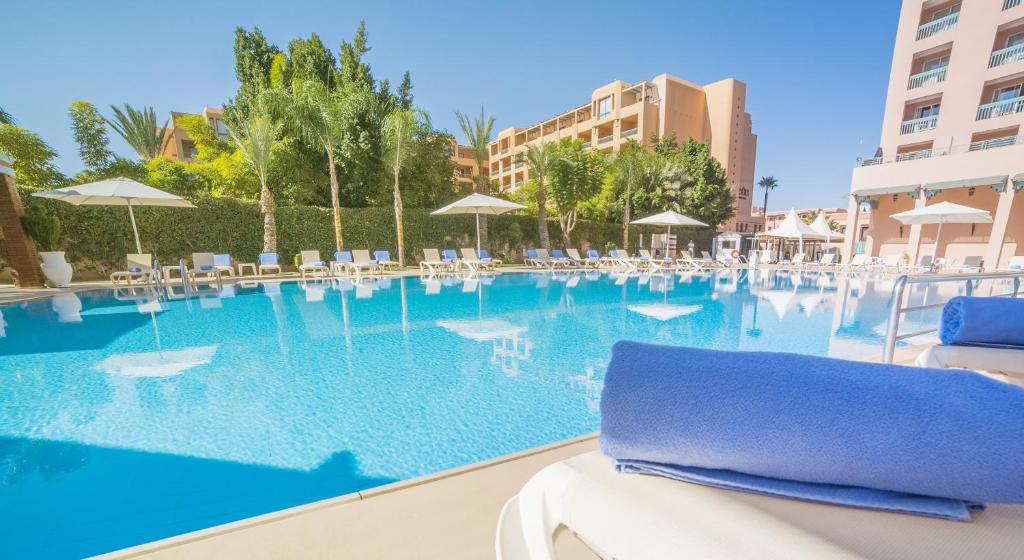 马拉喀什Grand Mogador Menara & Spa的度假村的游泳池,配有椅子和遮阳伞