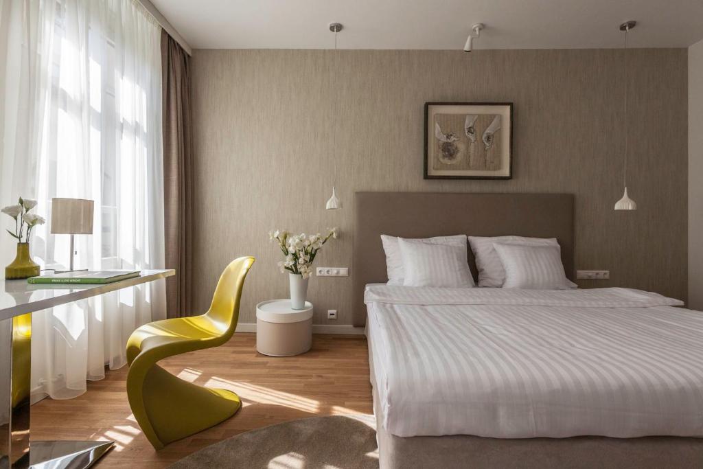 布达佩斯Casati Hotel - Adults Only的一间卧室配有一张床和一张黄色椅子