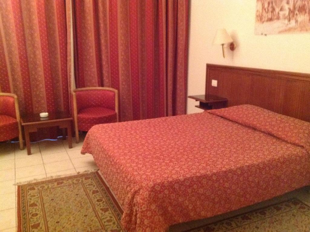 突尼斯埃尔哈娜国际酒店的酒店客房,配有一张床和两张红色椅子