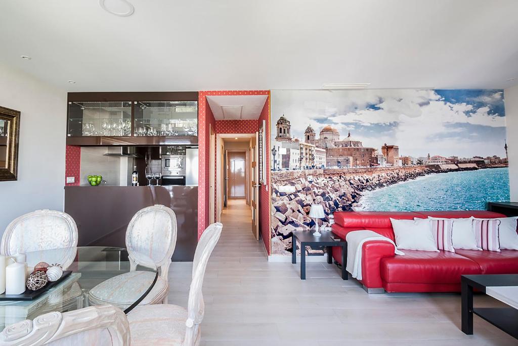 加的斯美景公寓的客厅配有红色的沙发和海滩绘画