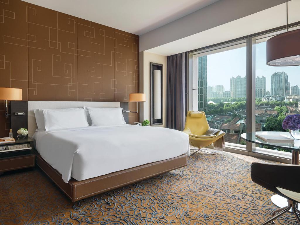 上海新天地朗廷酒店 的一间卧室设有一张大床和一个大窗户
