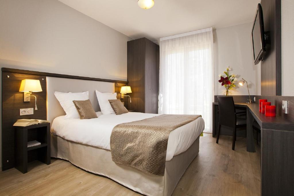 普罗旺斯艾克斯塞祖尔阿菲尔埃克斯普罗旺斯酒店的酒店客房设有一张大床和一张书桌。