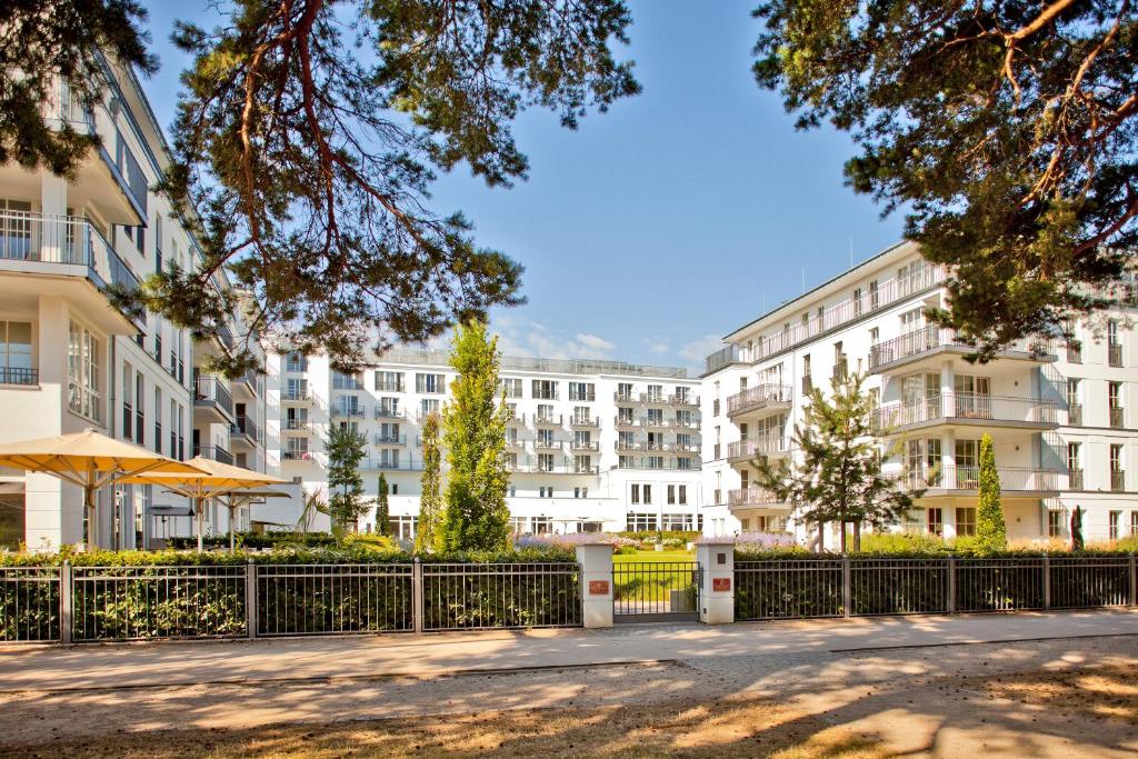黑灵斯多夫Steigenberger Grandhotel & Spa Heringsdorf的公寓大楼设有围栏和树木