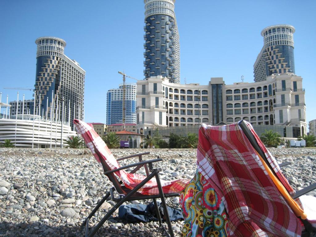 巴统My Batumi Apartments的两把椅子坐在城市前的海滩上