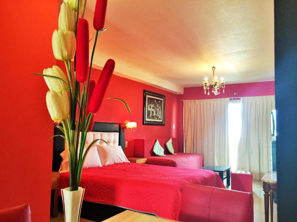 格塞尔镇Departamentos Sobre el Mar的红色的卧室,配有一张床和花瓶