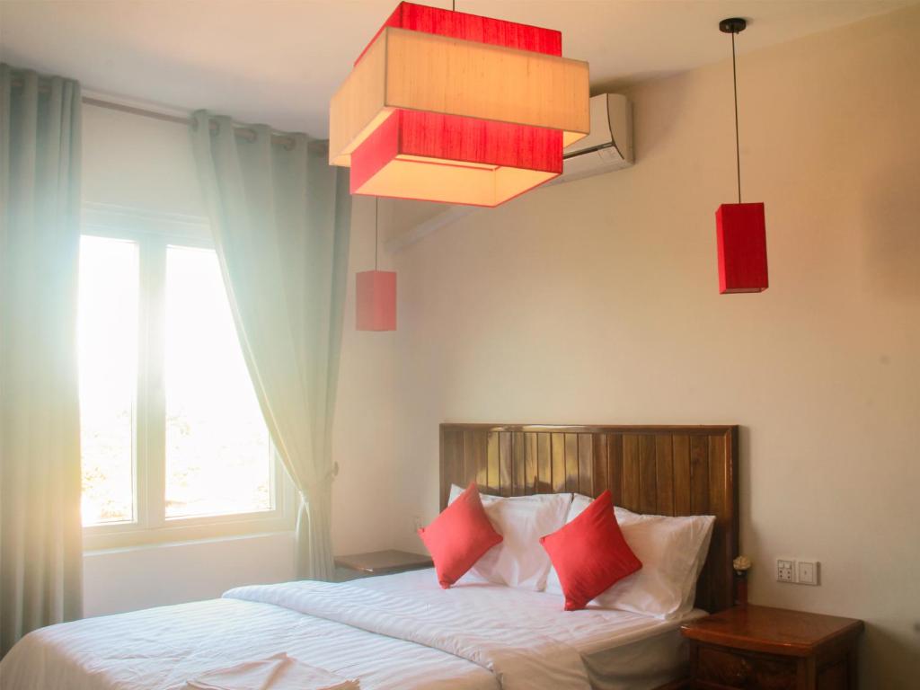 Bahal索卡旅馆的一间卧室配有一张带红色枕头的床和吊灯。