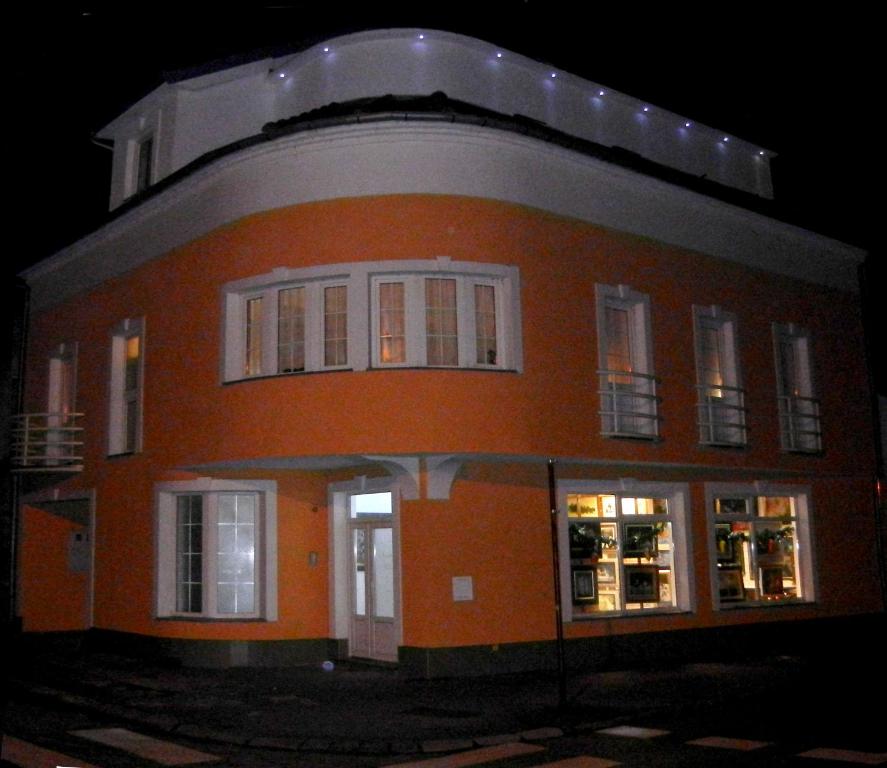 斯拉沃尼亚布罗德Villa Lucia - Apartments&Rooms的一座大型橙色建筑,晚上有白色的窗户