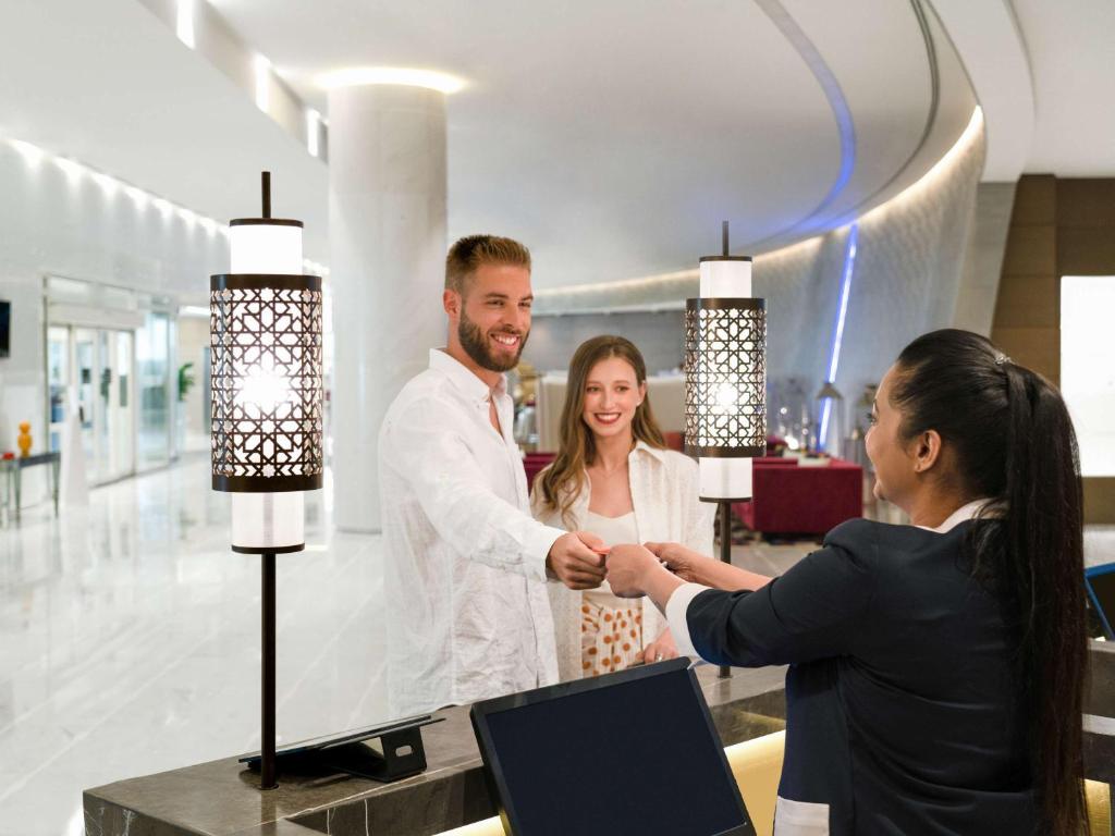 多哈Pullman Doha West Bay的男人和女人在商店里摇手