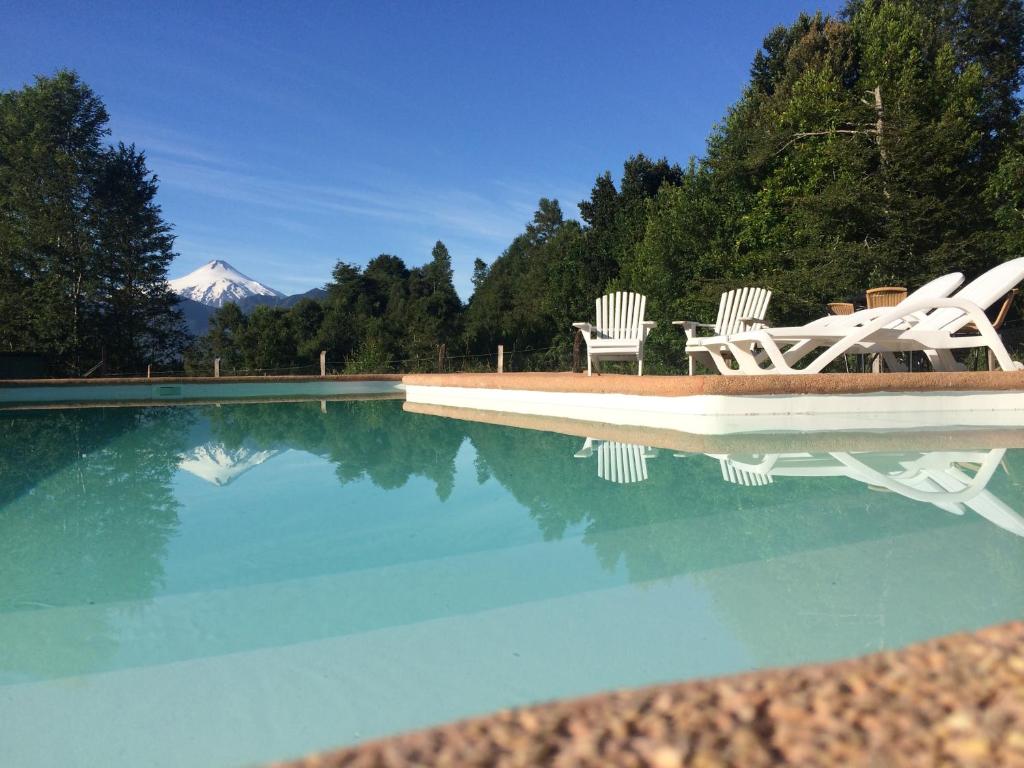 普孔Ecoreserva Quelhue Lodge y Cabañas的一个带两把椅子的游泳池,一个山底
