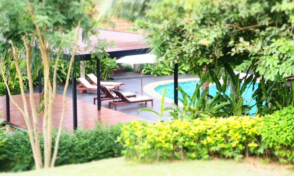 高兰Tropicana Lanta Resort的一个带长椅和树木的游泳池的度假酒店