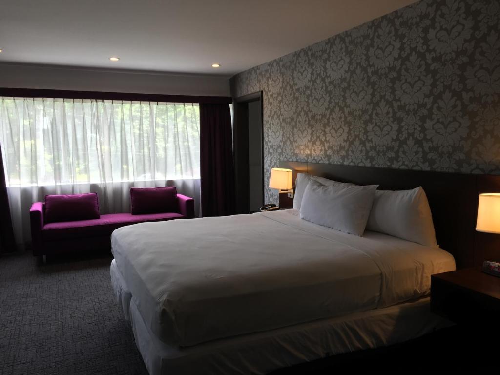 扬克斯皇家丽晶酒店的一间设有大床和窗户的酒店客房