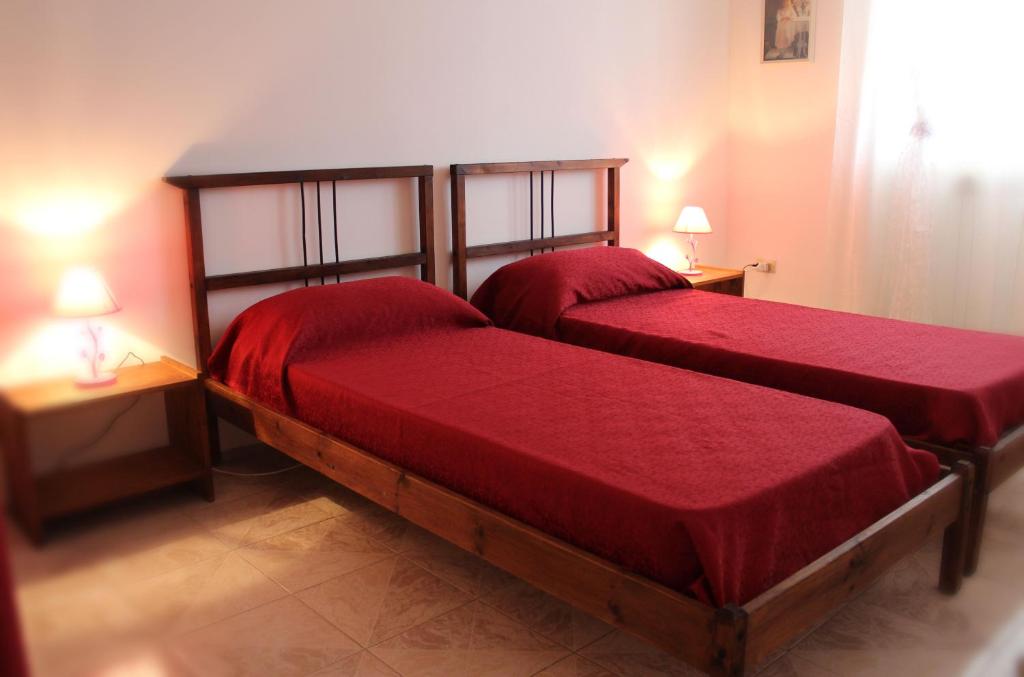 玛丽娜迪曼卡维萨Stelle Sul Salento Holiday Home的宿舍间内的两张床,配有红色床单和灯具