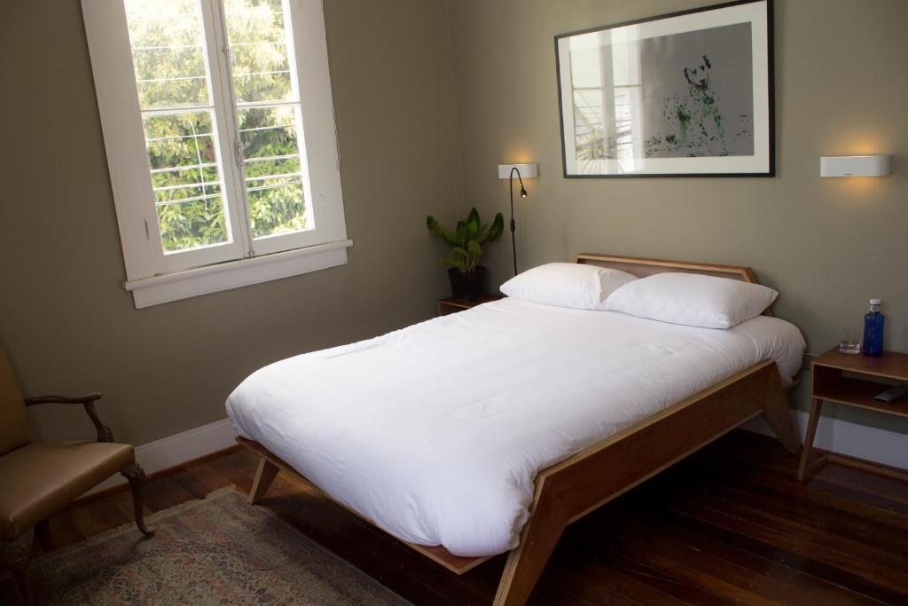 瓦尔帕莱索El Navegante B&B的一间卧室配有一张带白色床单的床和两个窗户。