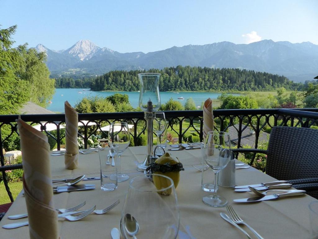 法克湖畔杜罗博拉赫雷斯曼湖滨酒店的配有玻璃杯和餐具的桌子,享有湖景
