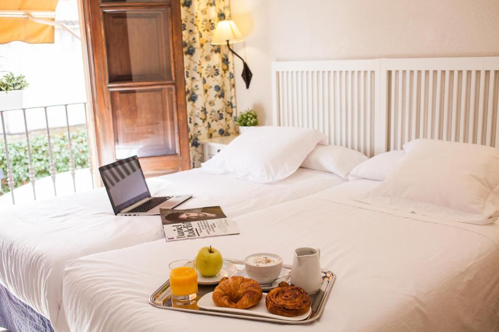 阿尔卡拉德荷那利斯米格尔·德·塞万提斯酒店的一张带食物托盘的床和一台笔记本电脑