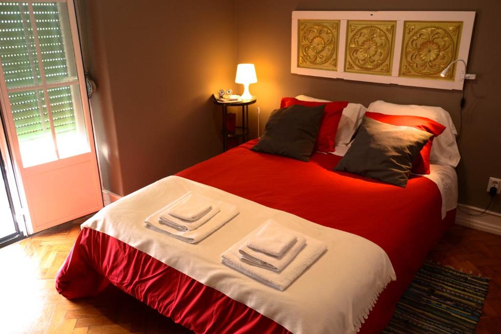 里斯本Alvalade II Airport Guest House的一间卧室配有一张带红色和白色床单的大床