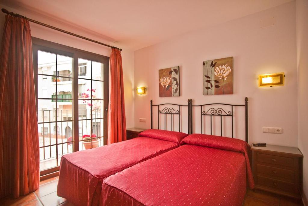 萨各夫雷纳帕洛马勒斯旅馆的一间卧室设有红色的床和窗户。