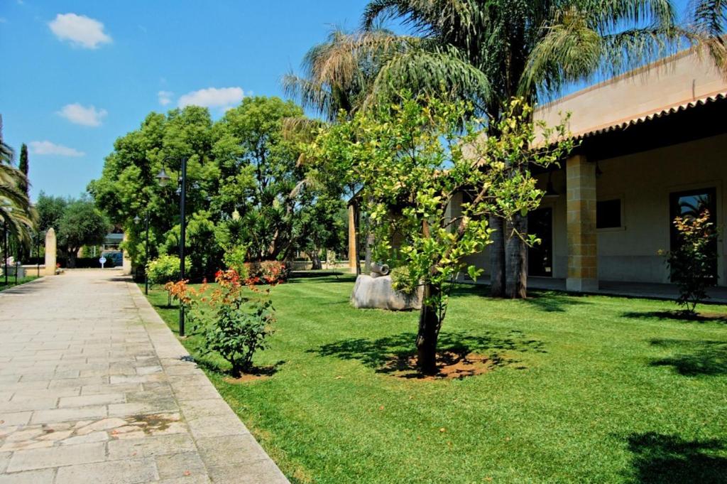 莱魁勒Antica Rudiae ricevimenti的一座绿树成荫的院子,毗邻一座建筑