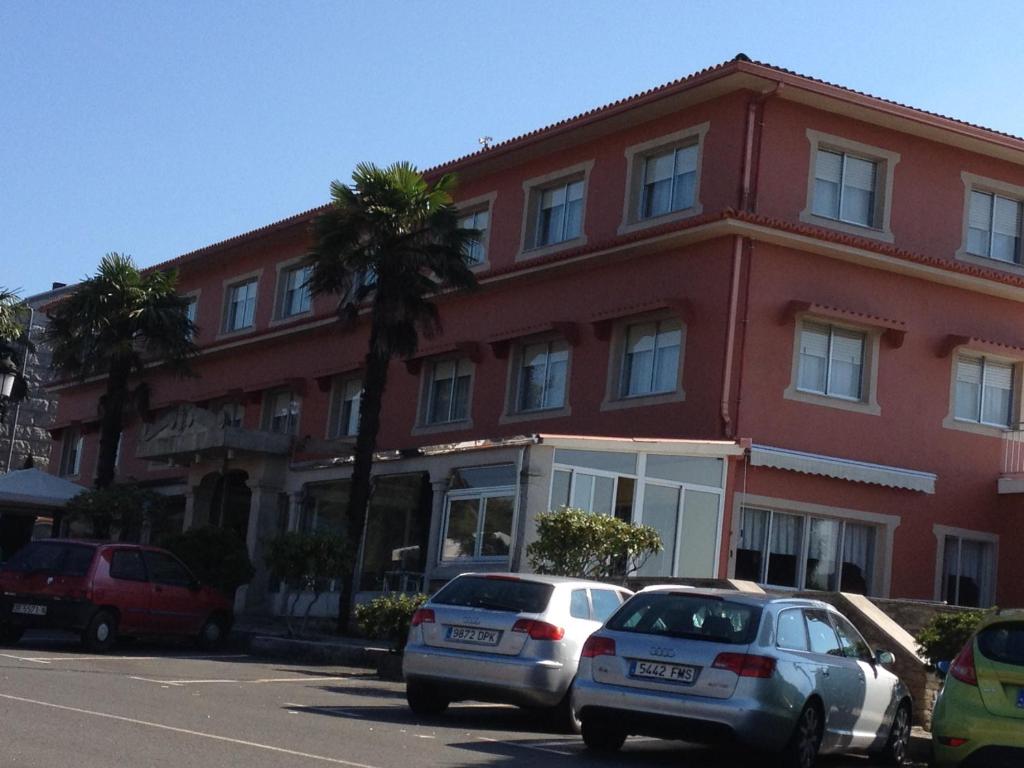 拉瓦克拉加尔卡斯酒店的两辆汽车停在一座红色建筑前面