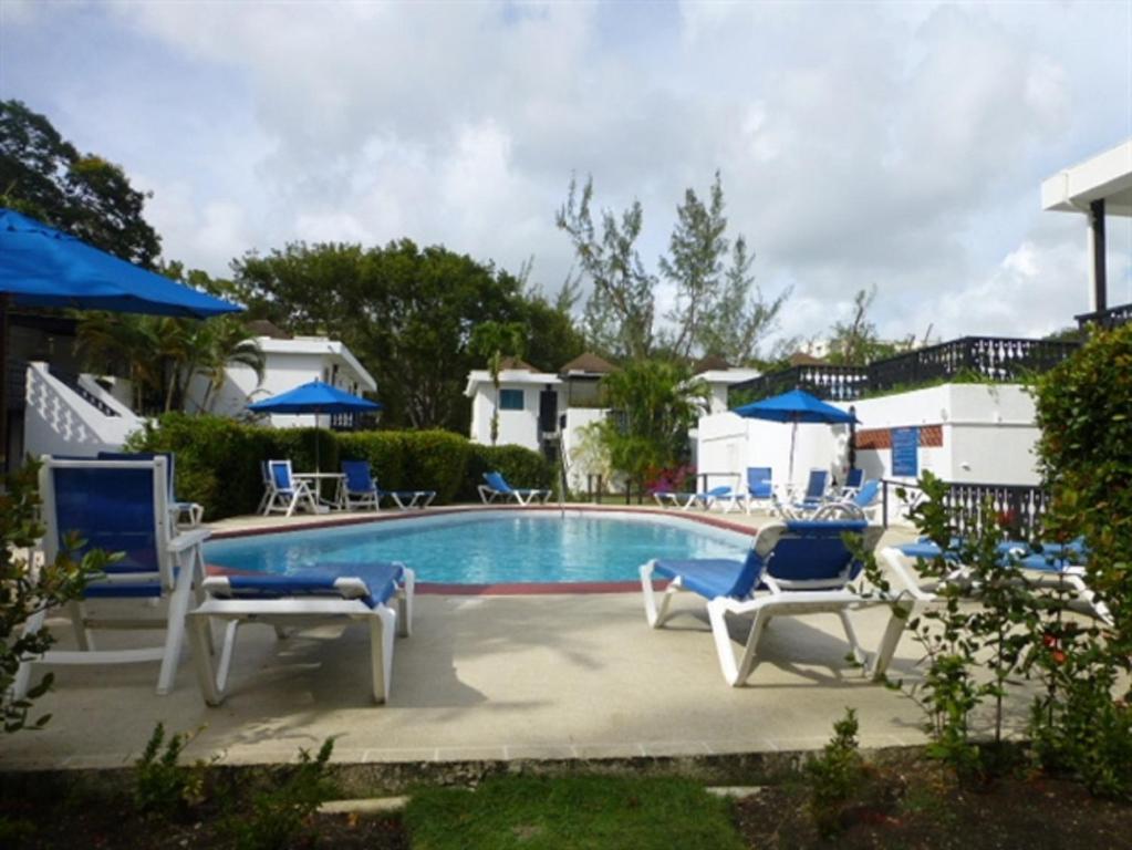 布里奇敦Rockley Golf Club, 2 bed 2 bath Pool, Tennis, Golf, Bar & Restaurant!的游泳池周围设有蓝色和白色的椅子
