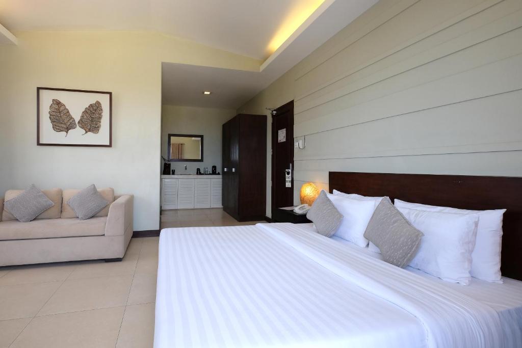 宿务阿尔巴吾诺酒店的卧室配有一张白色的大床和一张沙发。