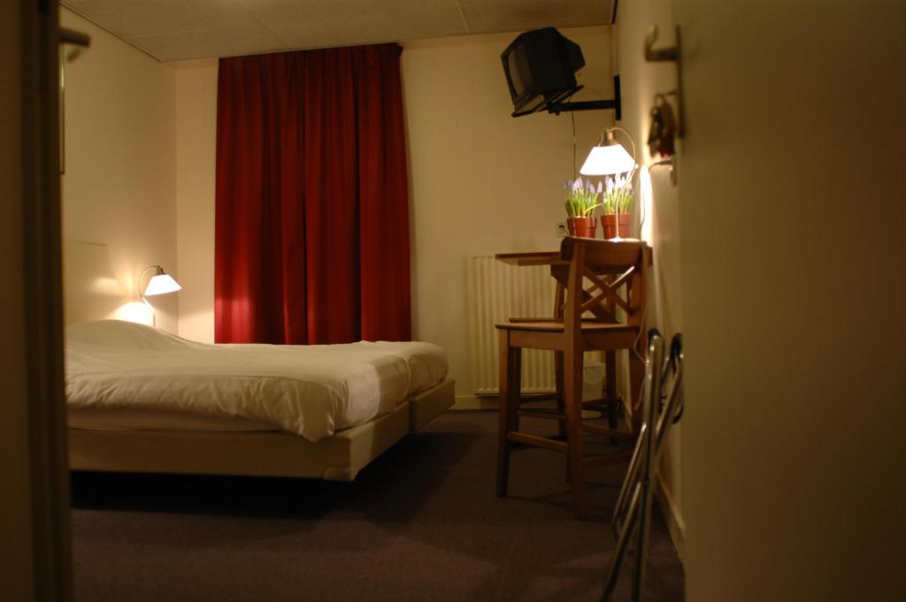 BalkHCR Teernstra的一间卧室配有床、桌子和红色窗帘