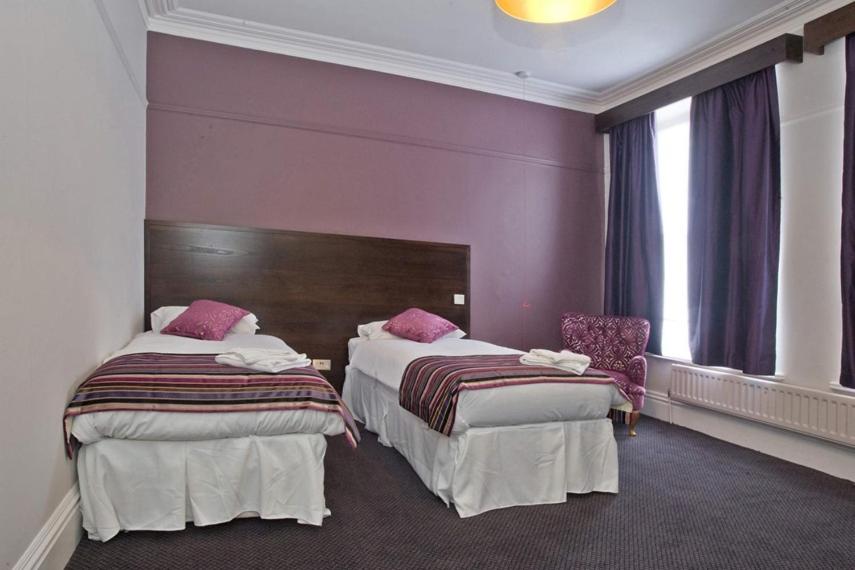 曼海德The Duke of Wellington Wetherspoon的紫色墙壁的酒店客房内的两张床