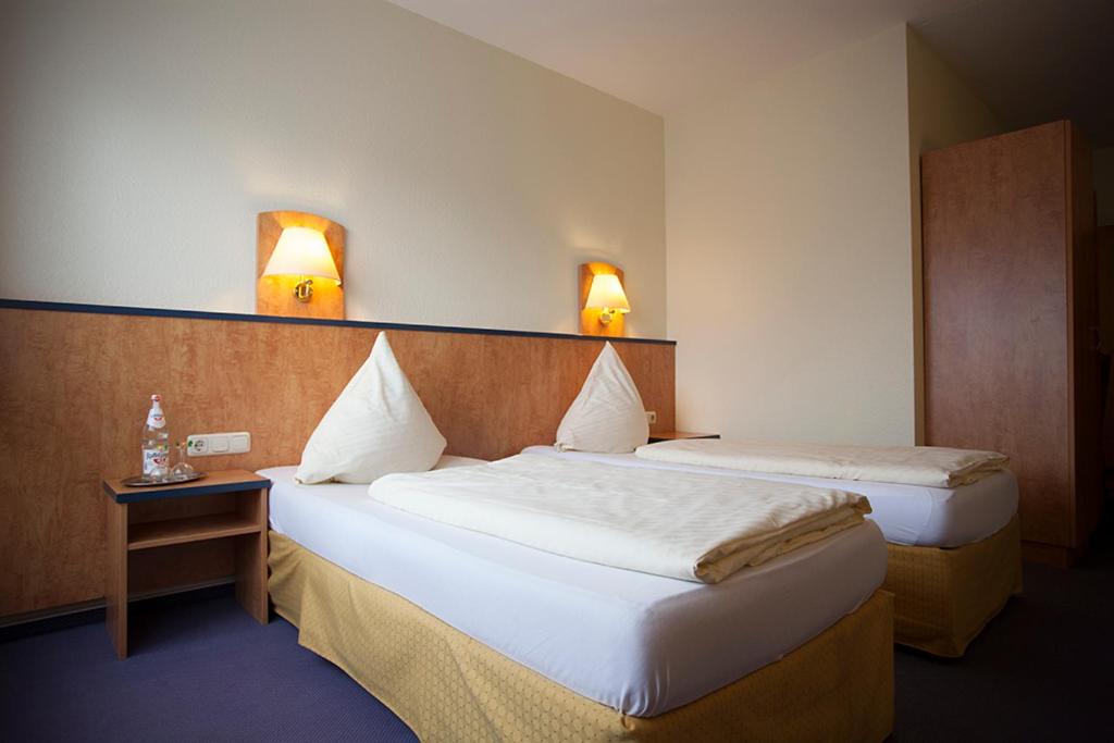 奥伯豪森豪斯友尼恩酒店的两间位于酒店客房的床,墙上有两盏灯
