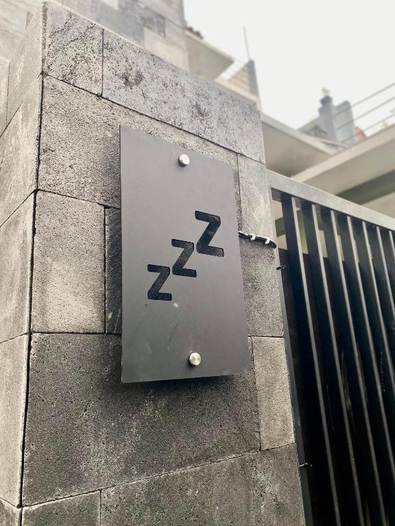 玛琅Zzz Hostel Malang的建筑物一侧的金属标志